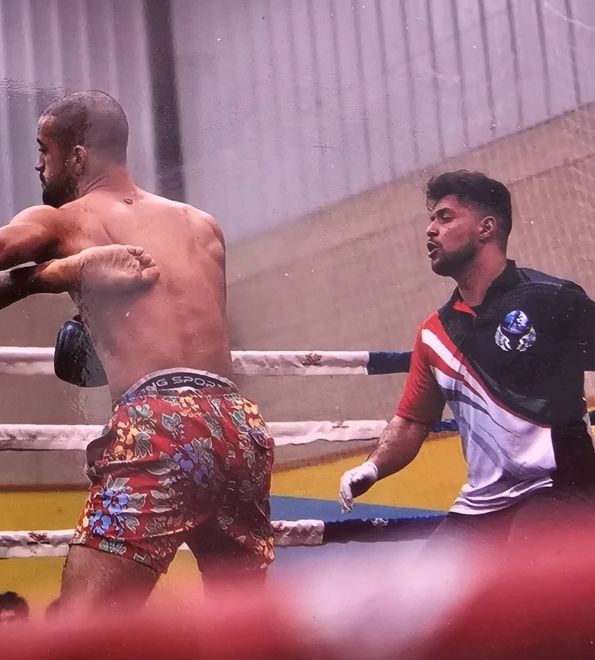 Nuno Da Rocha como árbitro durante un combate profesional de Muay Thai, con un luchador en primer plano