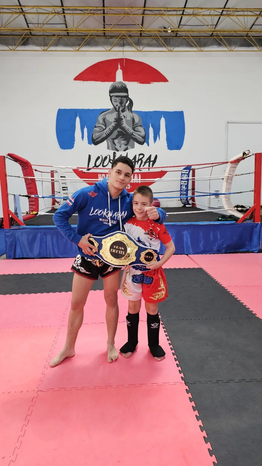 Dos alumnos jóvenes de Looknarai con un cinturón de competición en el gimnasio